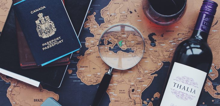 lupa-pasaporte-y-vino-sobre-mapa-del-mundo